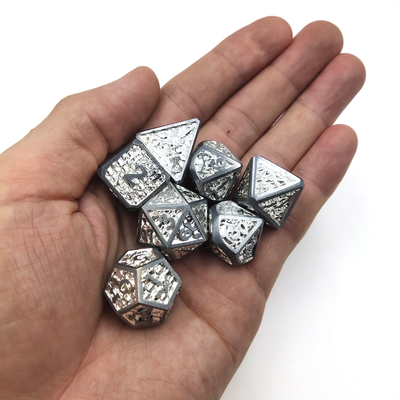 La main découpée par main de dé de RPG en métal de bord de carte a découpé des biens pour le polyèdre du monde sauvage